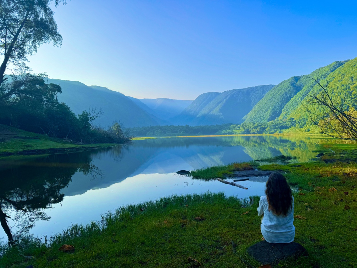 A woman seen from behind, facing a mountain lake