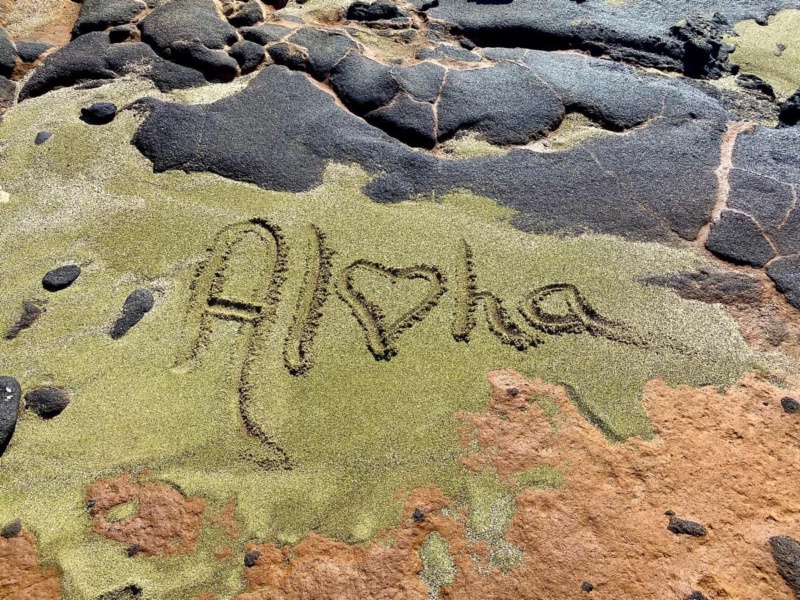 The word aloha written in green sand