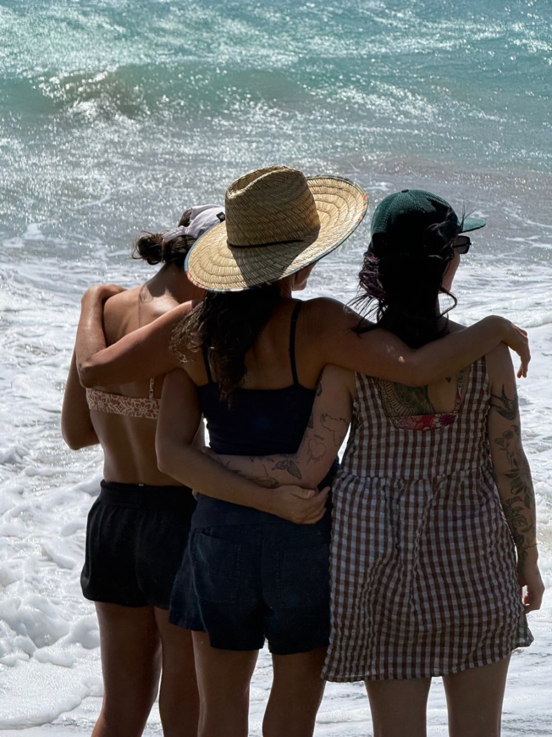 Three women seen from behind facing the sea