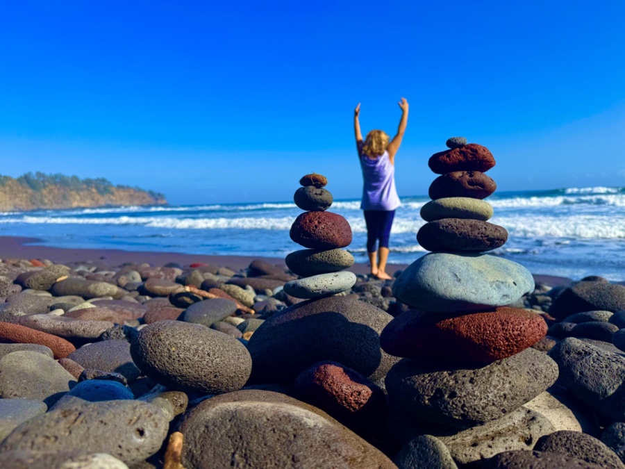 A woman celebrating with raised arms facing the sea